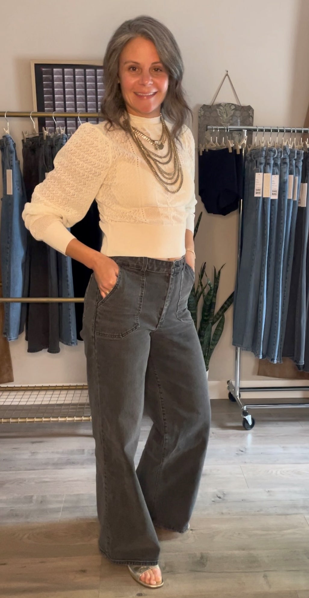 muriel wearing MURJER™'s morrison style shapewear jeans with built in patent pending shaping design & better butt™ technology to tuck your tummy & lift your booty. murjer™ launch collection hangs behind her in the background.